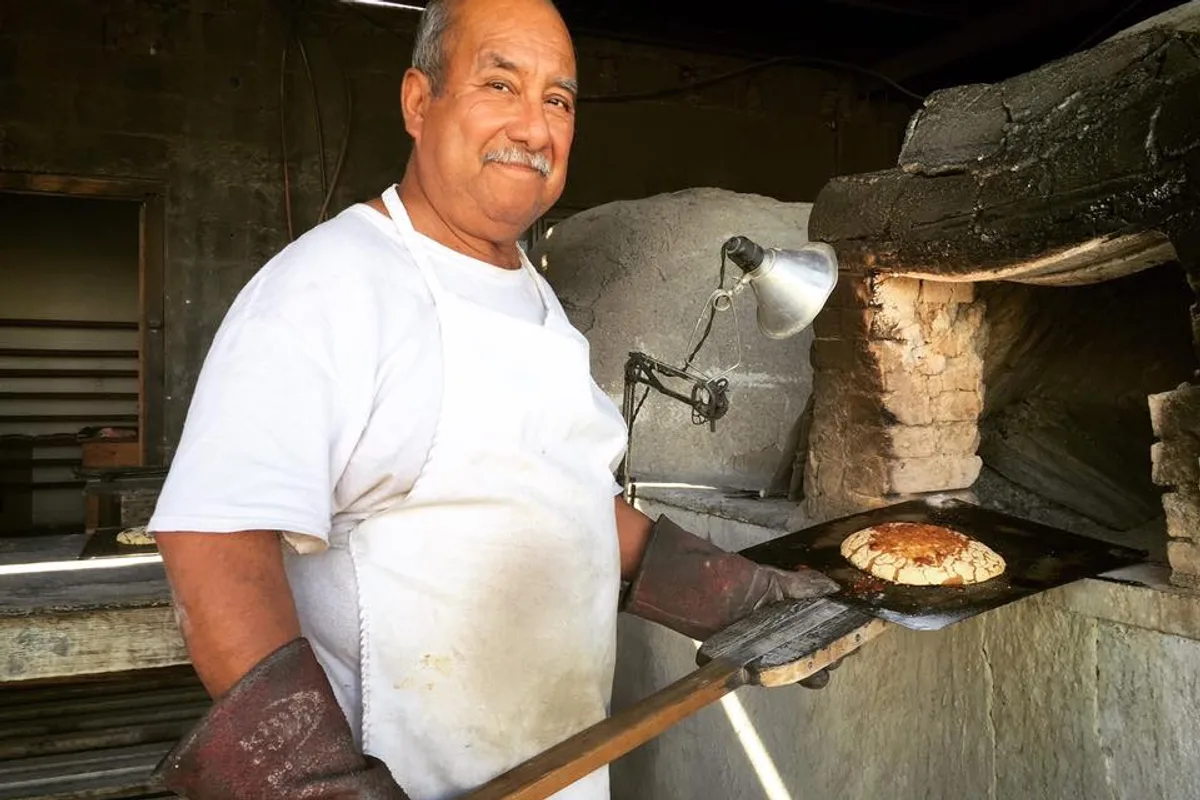 Panadero tradicional horneando pan casero en horno de leña en Bustamante, Nuevo León