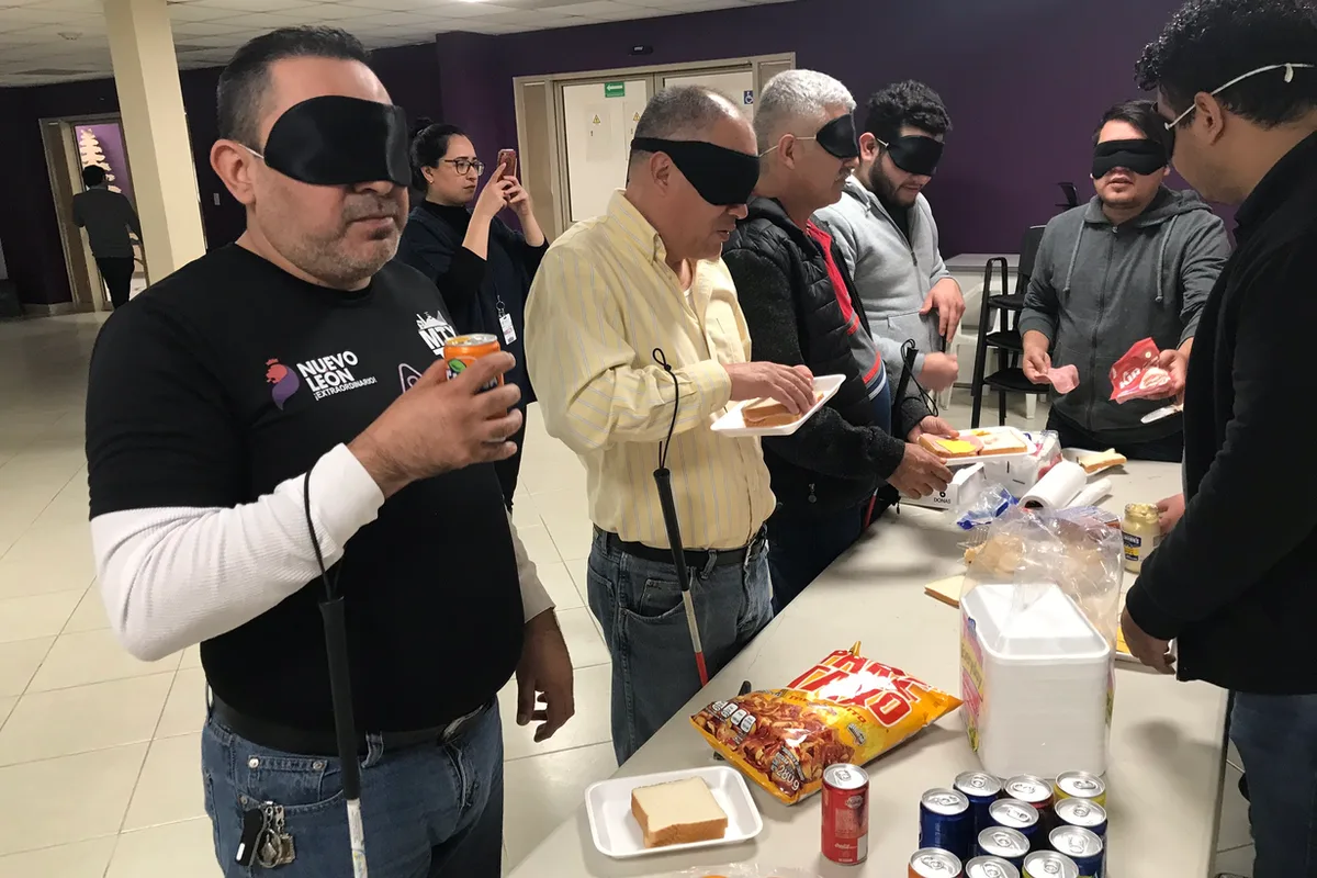 Grupo con los ojos vendados prueba alimentos como parte de un ejercicio de sensibilización sobre discapacidad