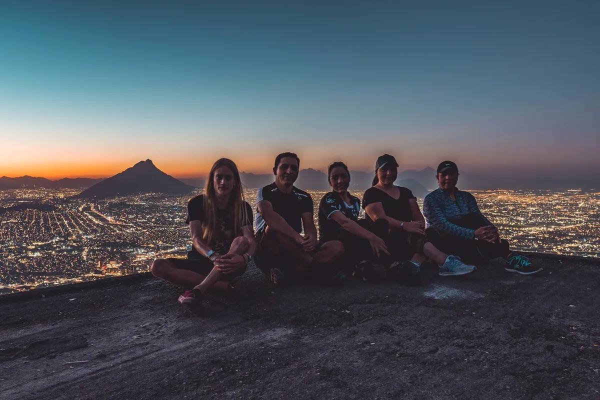 Grupo de excursionistas descansa en la cima del Cerro de la Silla mientras cae la noche