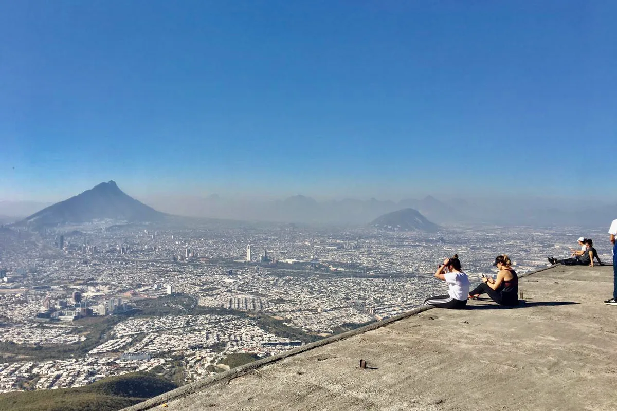 Excursionistas descansan en la cima del Cerro de la Silla con vista panorámica de Monterrey