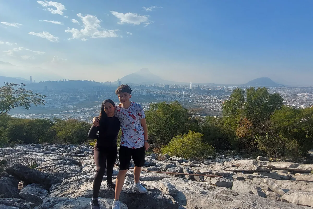 Pareja de excursionistas posa en la cima del Cerro de la Silla con la ciudad de fondo