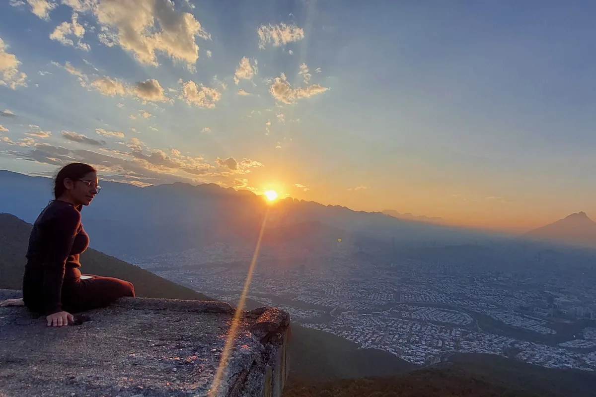 Excursionista contempla el atardecer sentada al borde de la cima del Cerro de la Silla