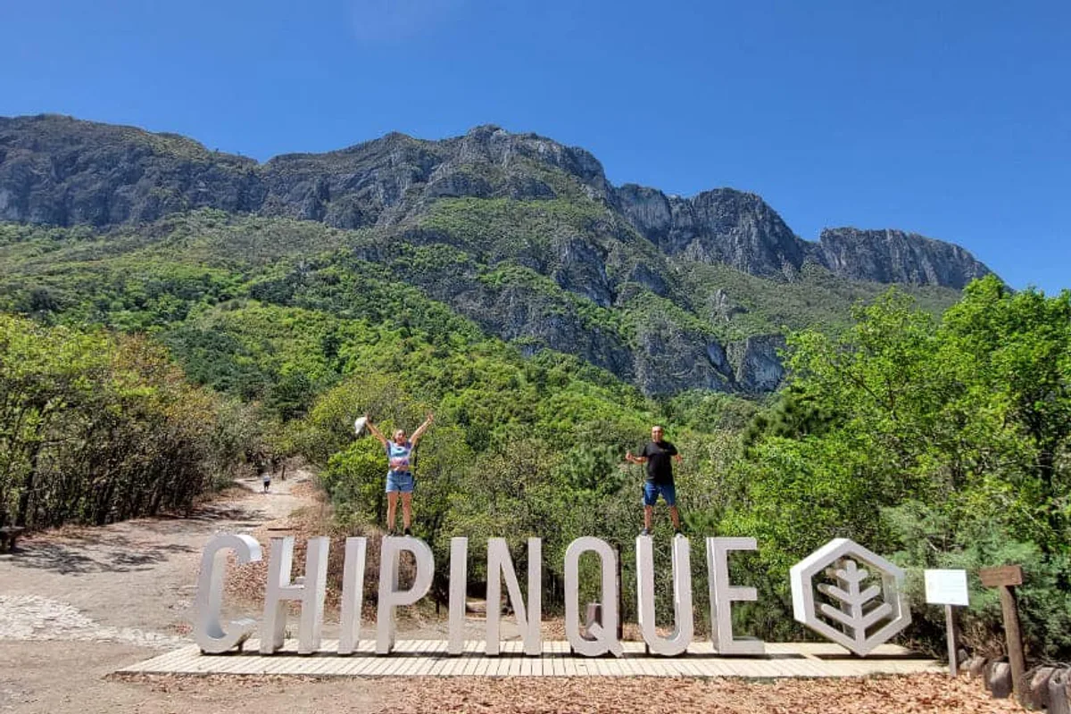 Excursionistas celebran junto al letrero de Chipinque con la sierra de fondo en Monterrey