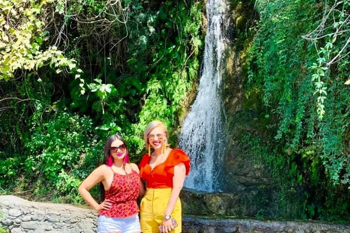 Dos amigas posan sonrientes frente a la cortina de agua de la Cascada Cola de Caballo
