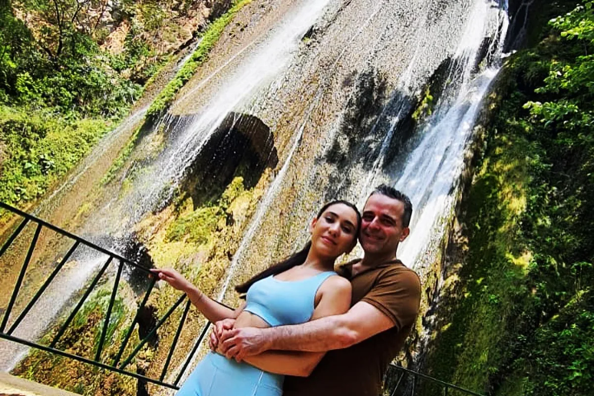 Pareja abrazada frente a la gran cascada Cola de Caballo iluminada por el sol en Nuevo León