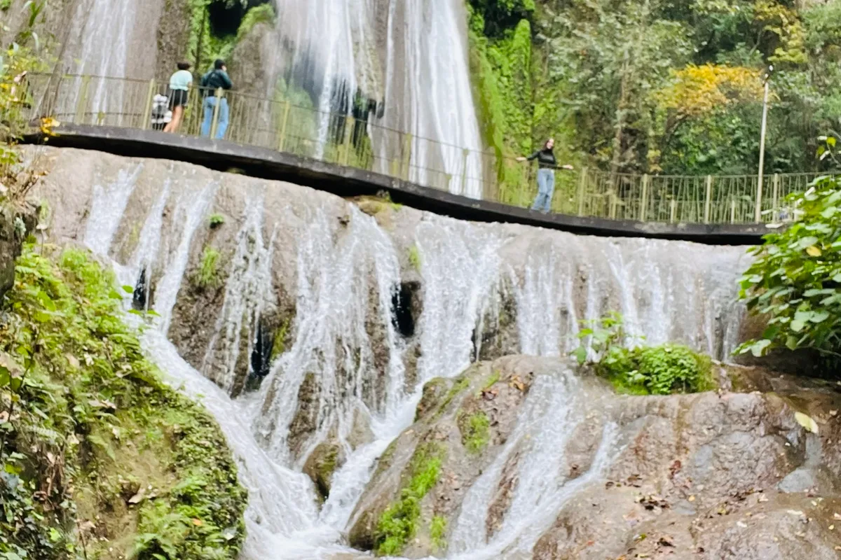 Cascada Cola de Caballo cayendo en terrazas de piedra caliza bajo un puente colonial en Santiago, Nuevo León