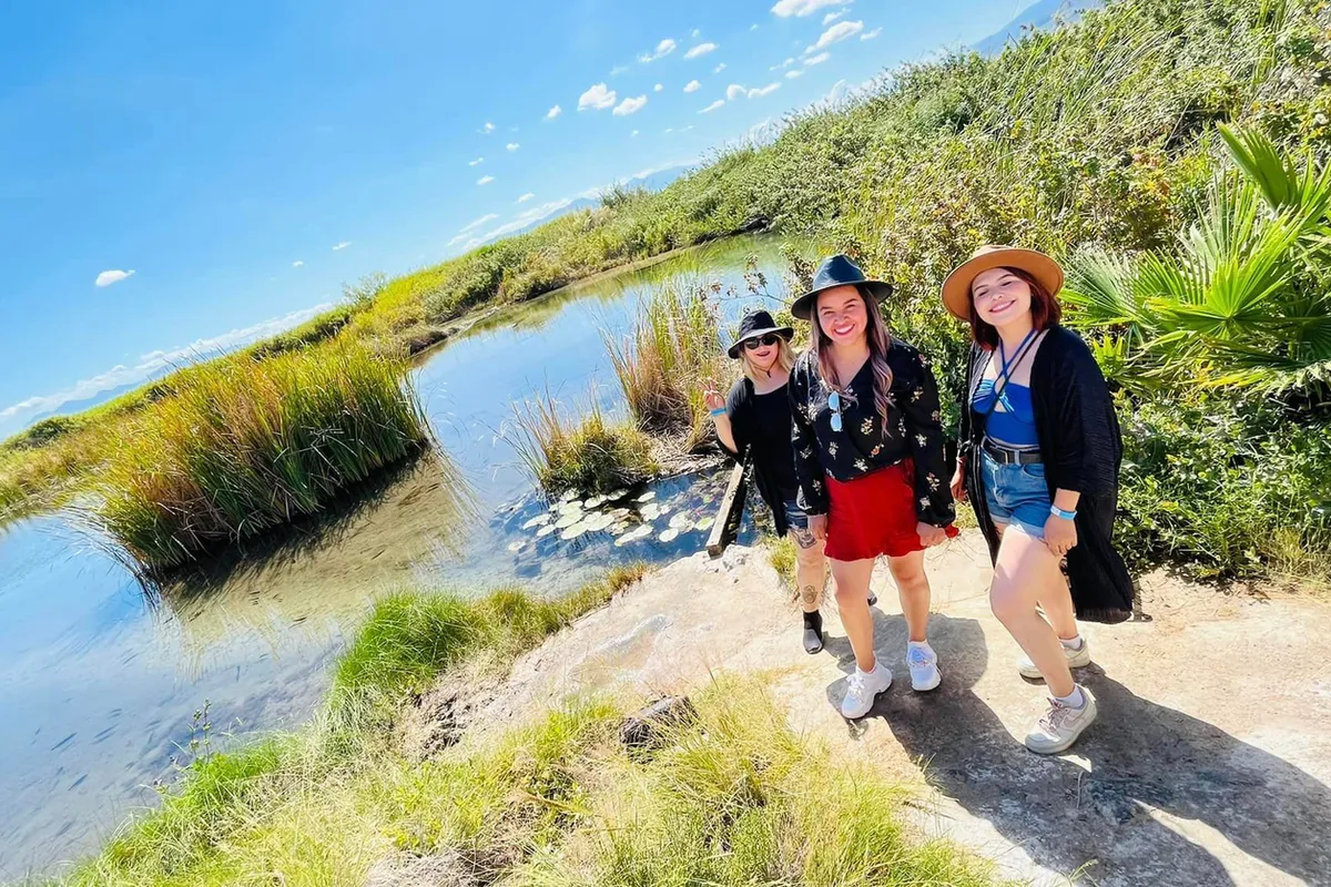 Grupo de amigas caminando junto a una laguna turquesa rodeada de vegetación en Cuatro Ciénegas