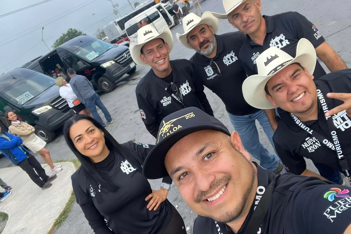Equipo de guías de MTY Tour con sombreros vaqueros posa junto a las vans de la flota