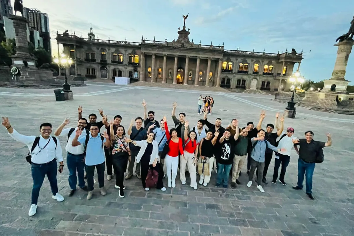Gran grupo turístico posa frente al Palacio de Gobierno de Nuevo León iluminado al atardecer
