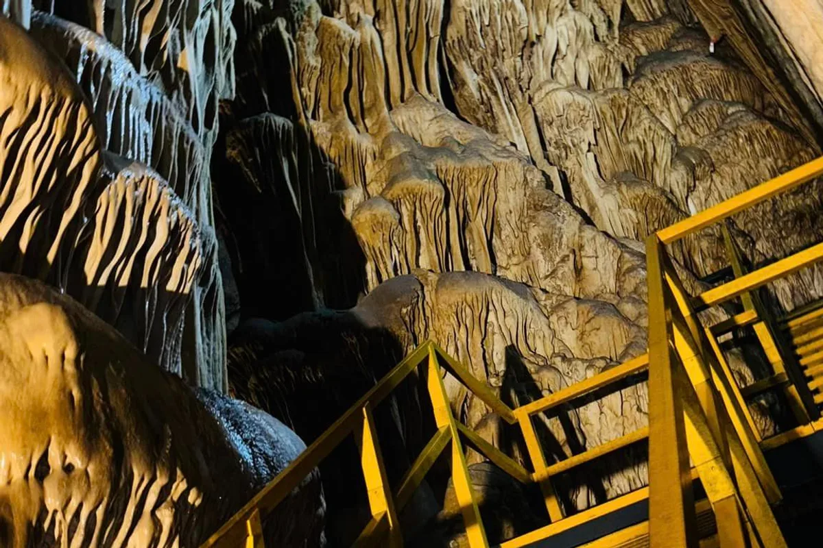 Escalera amarilla entre imponentes estalactitas dentro de las Grutas de García