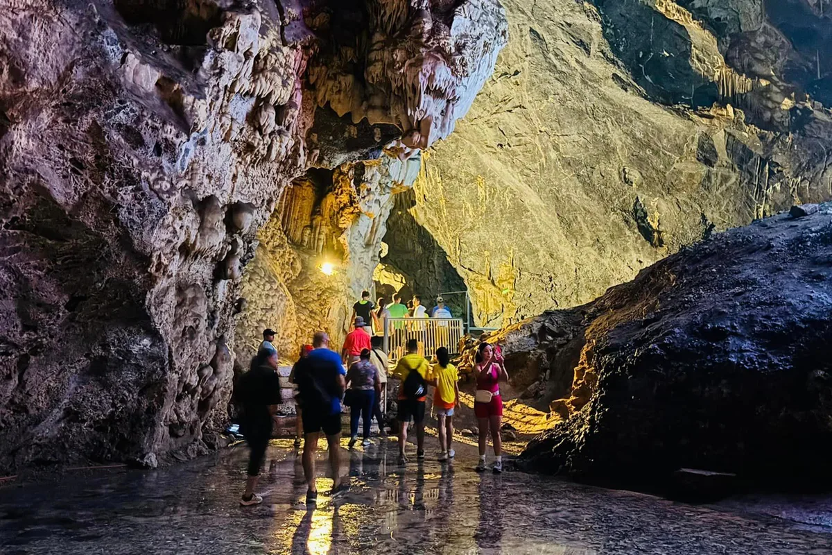Turistas recorren el sendero interior de las Grutas de García iluminado con luces cálidas y azules