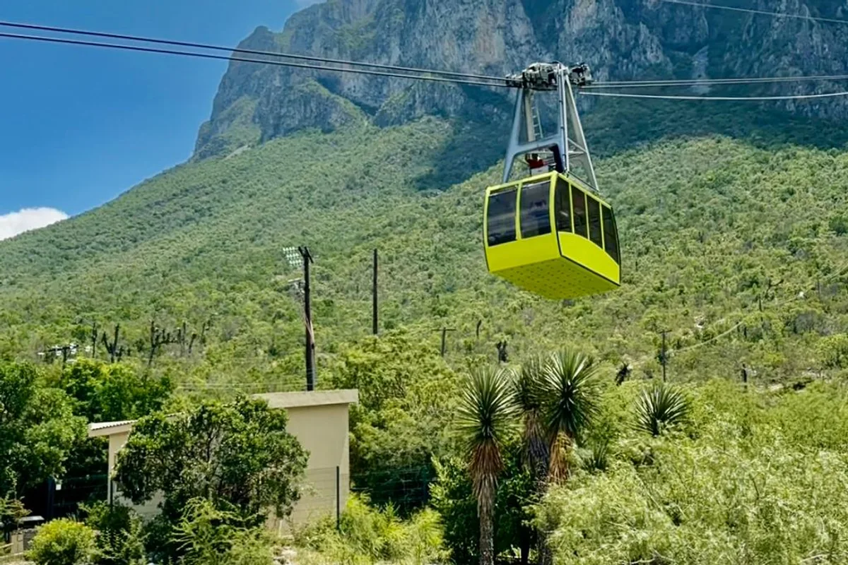 Teleférico de las Grutas de García cruza sobre el bosque con la Sierra Madre de fondo