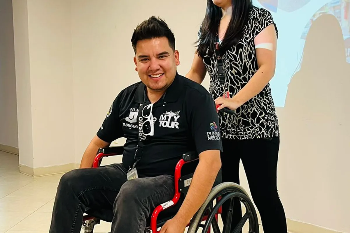 Colaborador en silla de ruedas sonríe junto a una compañera de Monterrey Tour durante la capacitación
