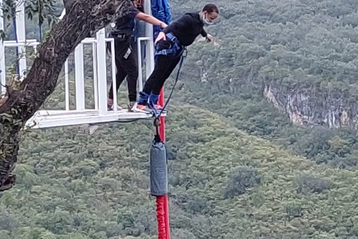 Turista saltando bungee desde una plataforma con vista al cañón boscoso del pueblo mágico