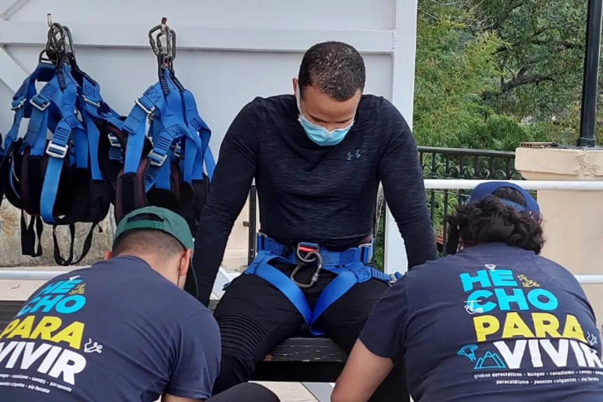 Guías preparando el arnés de un visitante antes de la tirolesa en el parque de aventura