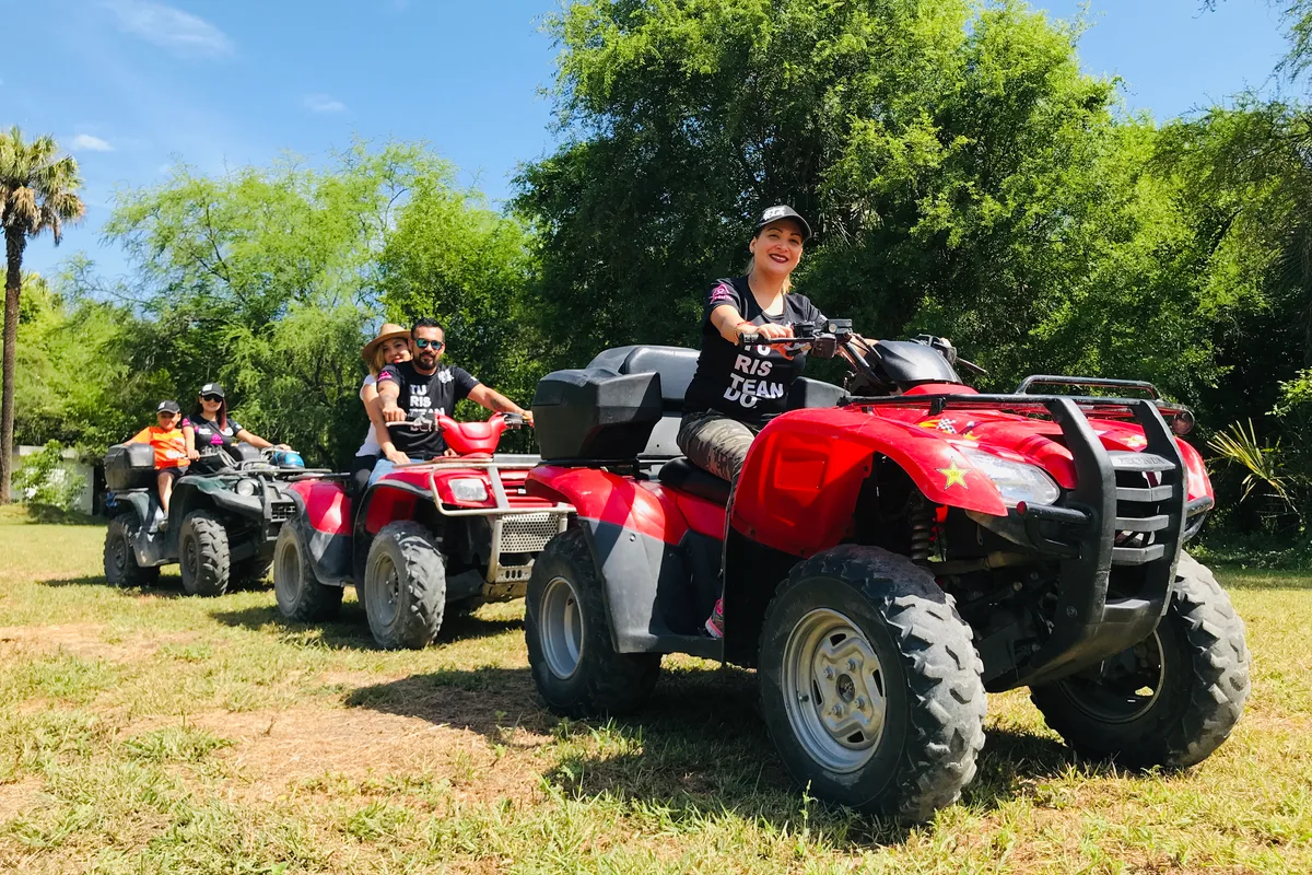 Grupo en cuatrimotos rojas avanza por un sendero boscoso durante el tour de motos todo terreno