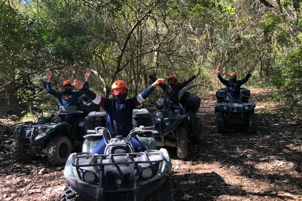 Cuatrimotos avanzan en fila por un sendero boscoso con el grupo festejando
