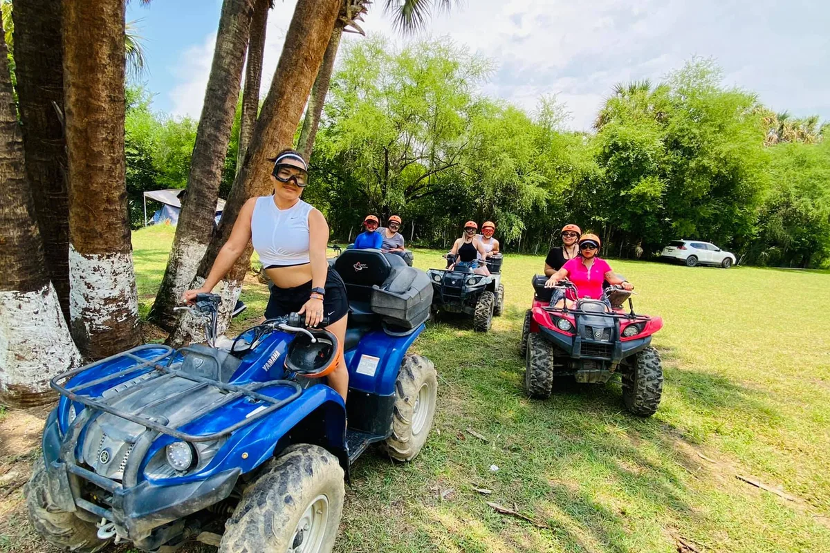 Mujer conduce su cuatrimoto azul entre palmeras durante el recorrido todo terreno