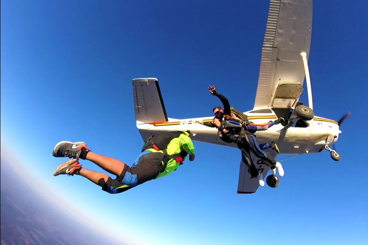 Instructor y pasajero saltan en paracaídas tándem desde la puerta de la avioneta