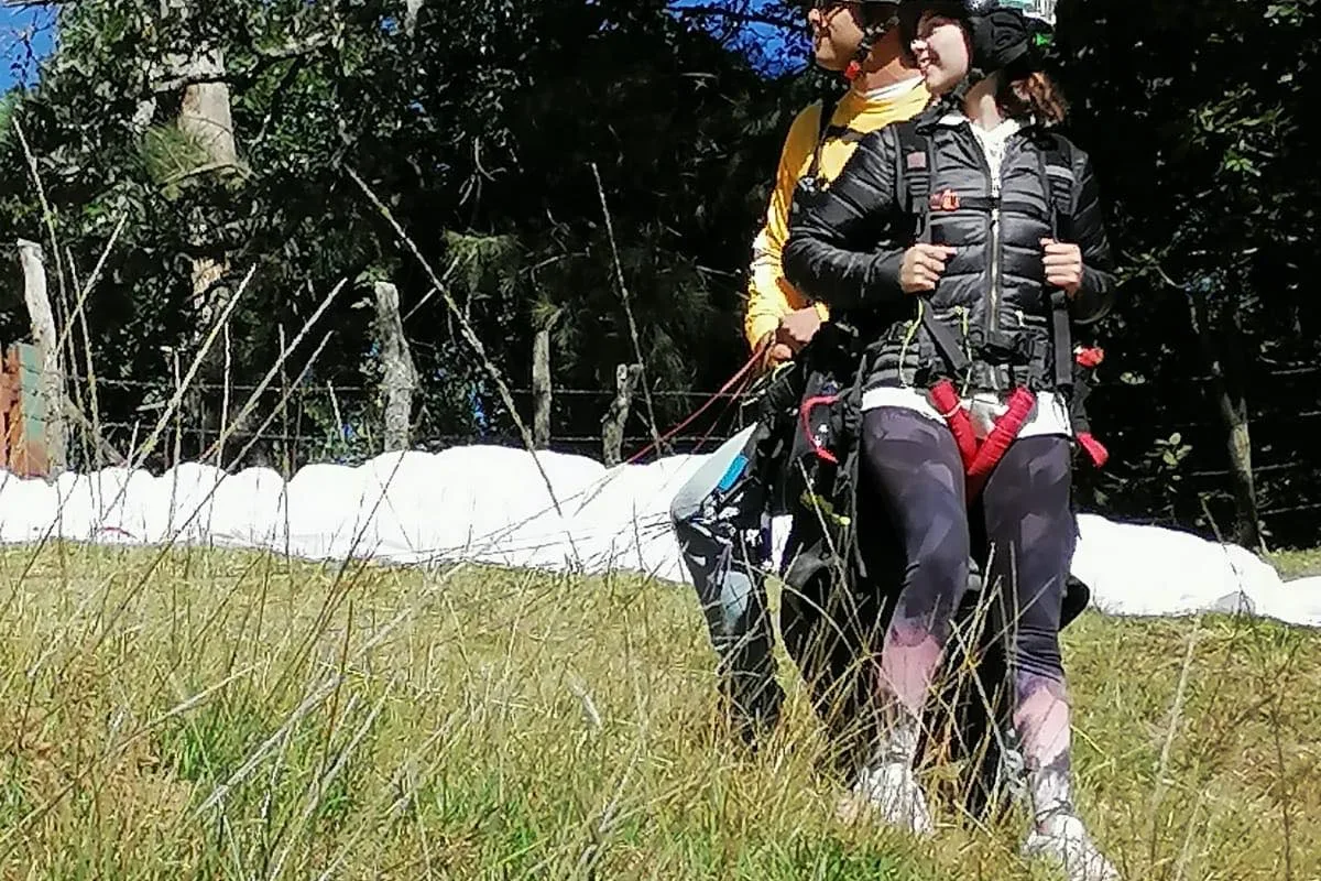 Turistas se preparan con el equipo de seguridad antes de despegar en parapente