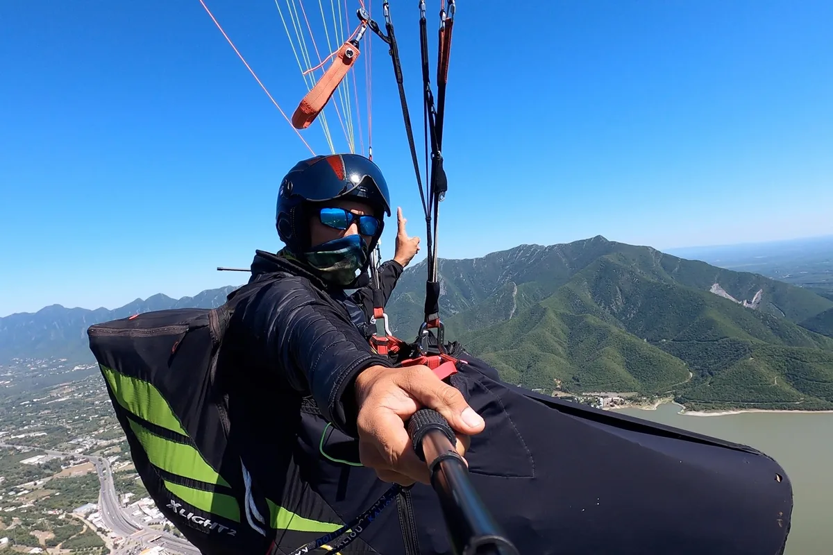 Piloto toma selfie en pleno vuelo de parapente sobre la presa y la sierra