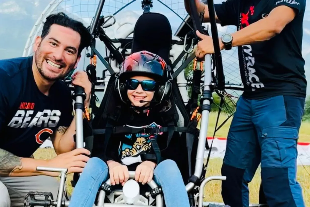 Pasajera celebra con los brazos abiertos durante un vuelo en paratrike al amanecer