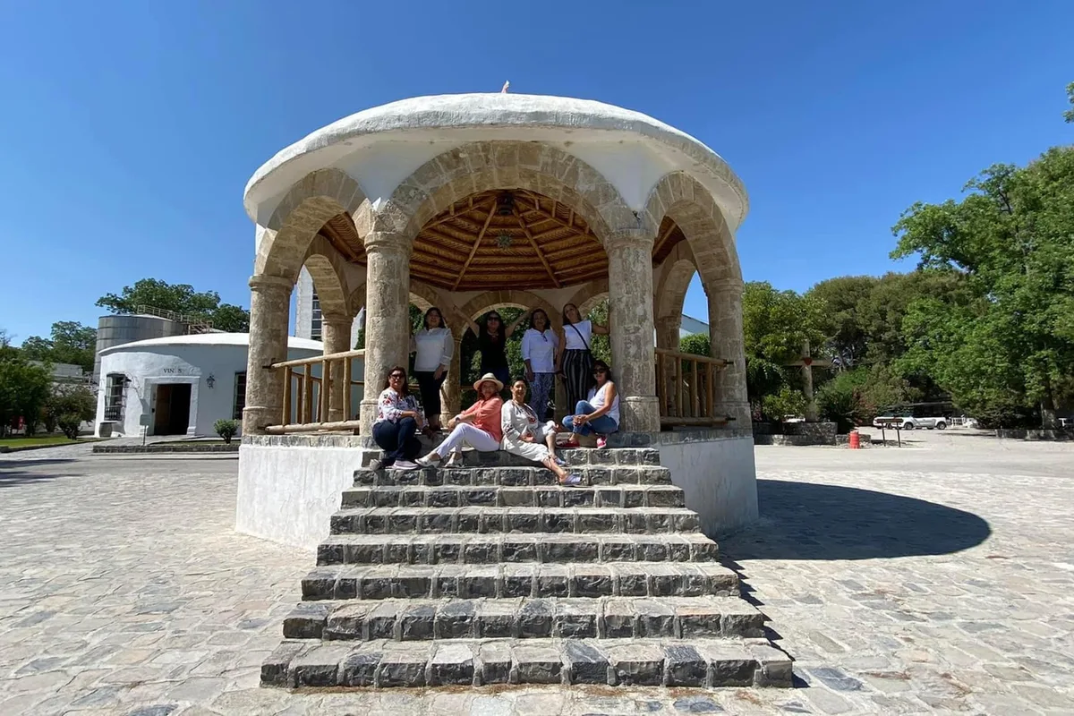 Grupo de turistas descansando en el kiosco de cantera del jardín principal de Parras