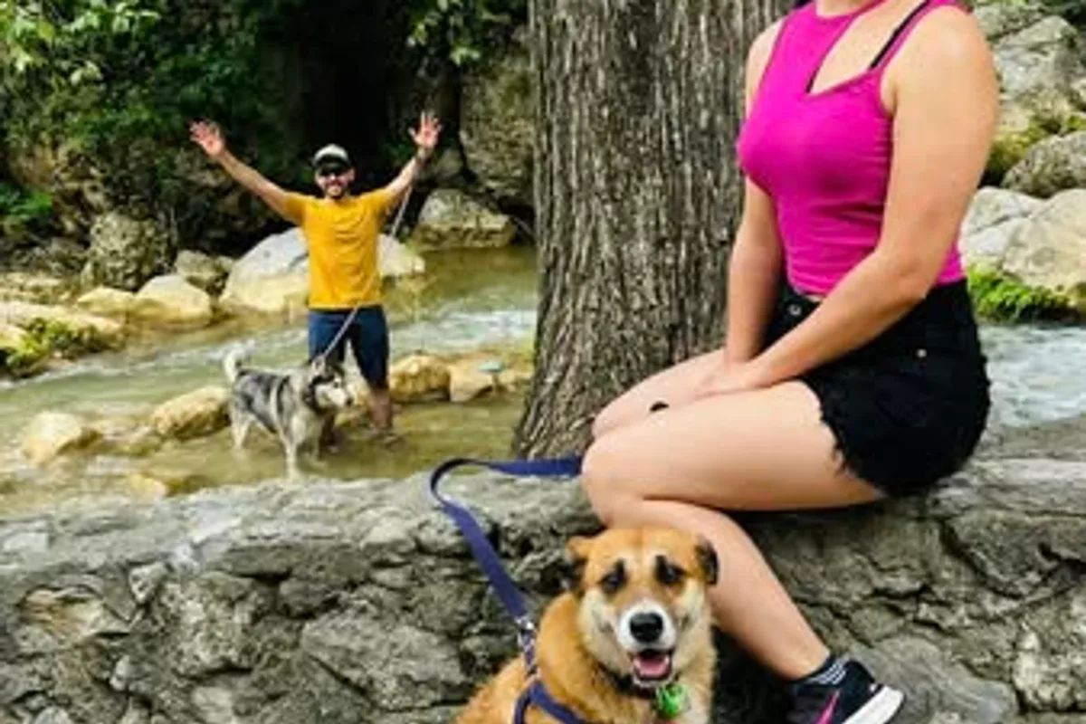 Pareja celebra junto a sus dos perros sobre las rocas de un río durante un tour pet-friendly