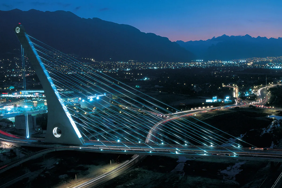 Puente del Papa iluminado al anochecer con el horizonte de San Pedro Garza García y la Sierra Madre