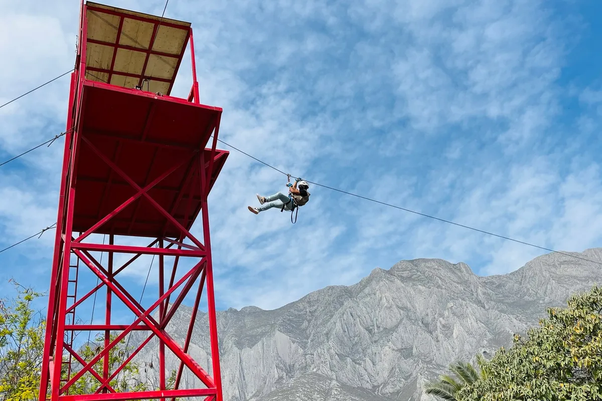 Tirolesa cruza sobre una torre roja con la Sierra Madre de fondo en Xenpal
